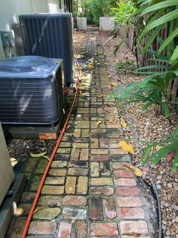 Pressure washing specialist removing embedded grime from textured patio surface with controlled equipment