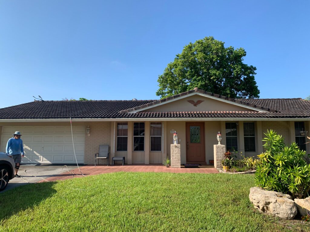 Technician applying roof cleaning treatment evenly across stained residential shingles