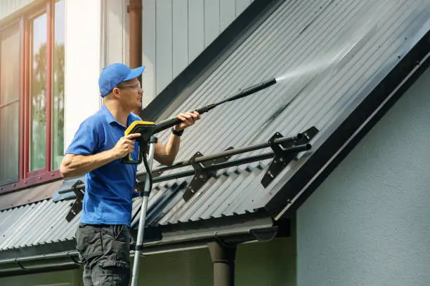 Technician cleaning algae-stained roof on busy West Palm Beach residential property