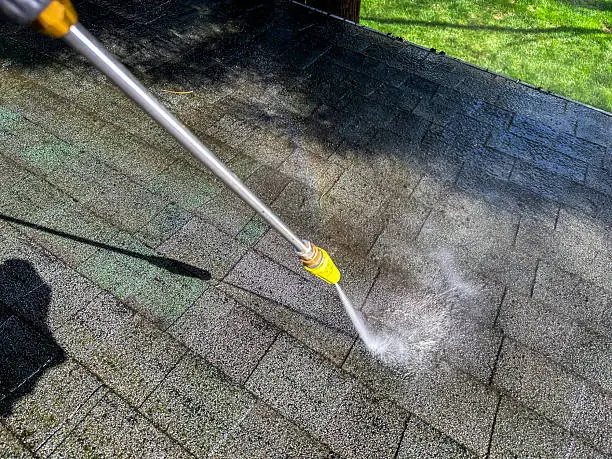 Technician cleaning algae-stained tile roof on Delray Beach home before weekend showing