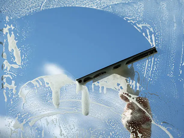 Skilled window cleaner checking glass clarity and edge buildup on large exterior pane