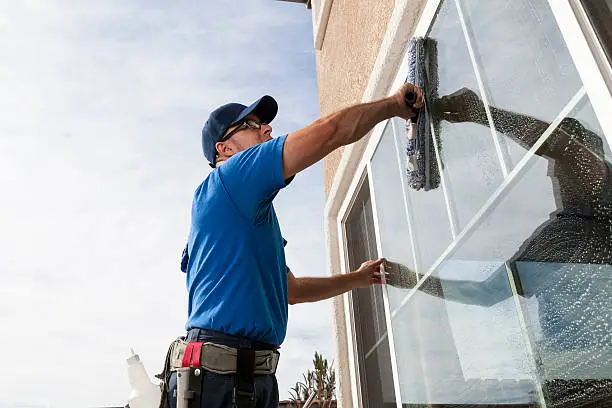 Cleaner wiping salt film from large residential windows before a Boca Raton open house